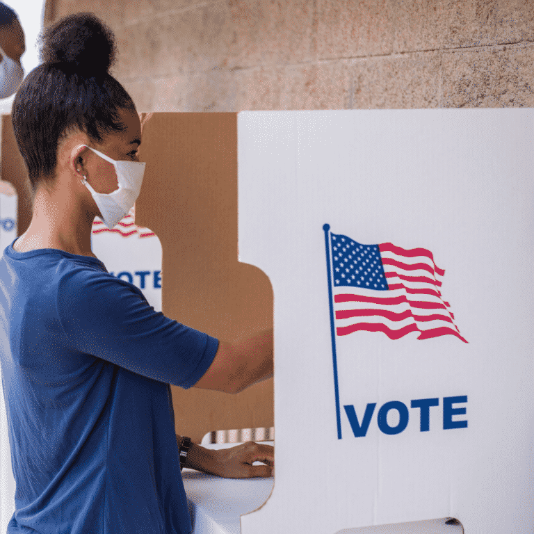 How Will the Election Impact Real Estate Women voting in booth with mask on